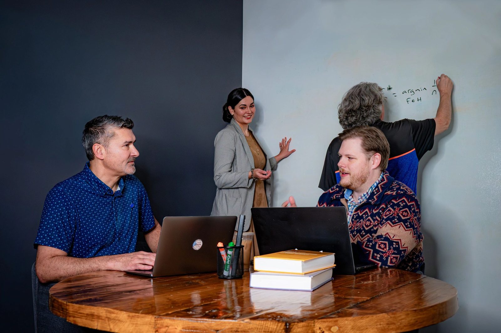 Four members of the team working at a whiteboard, one writing an argmin expression